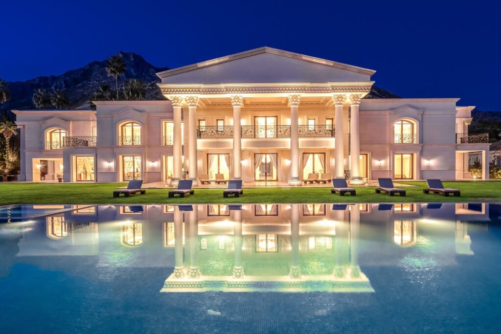 Fachada iluminada de Villa Bellagio en Marbella, con piscina infinita y arquitectura clásica inspirada en palacios europeos.