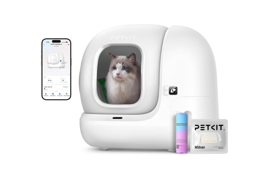 Arenero automático PETKIT Pura MAX 2 con un gato real en su interior, acompañado de un smartphone con la app conectada y accesorios como el desodorizador PETKIT N50 2.0.
