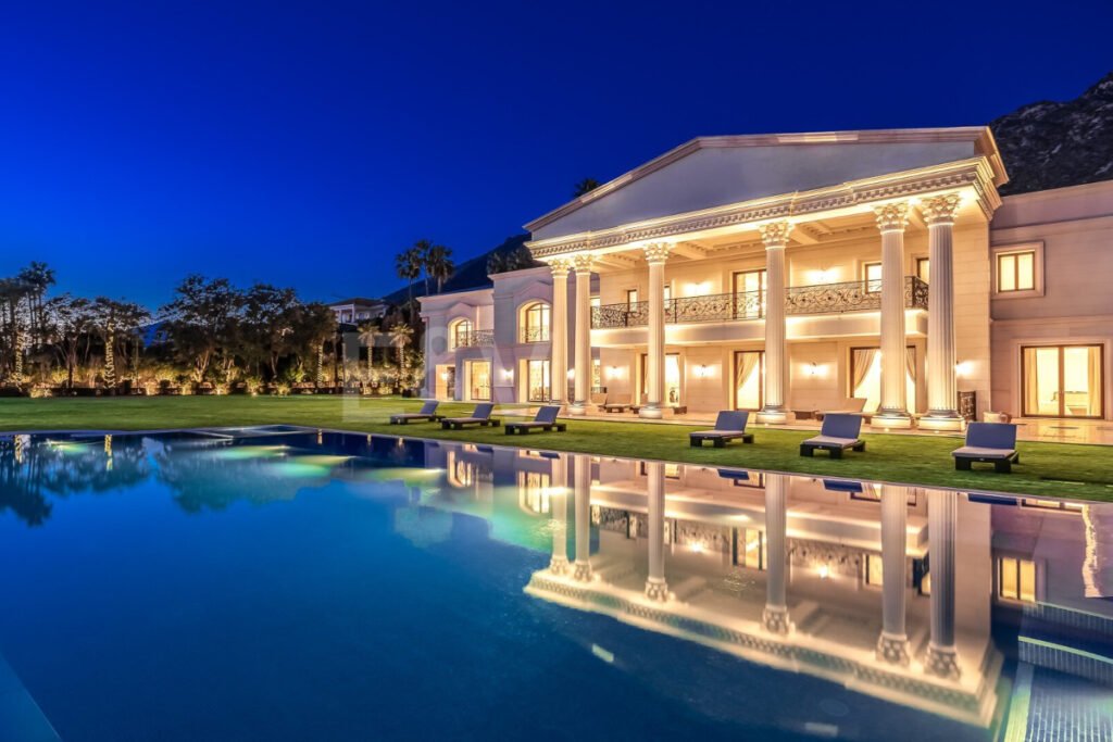 Villa Bellagio iluminada al anochecer con piscina reflejando su fachada clásica y jardín amplio en Sierra Blanca, Marbella.