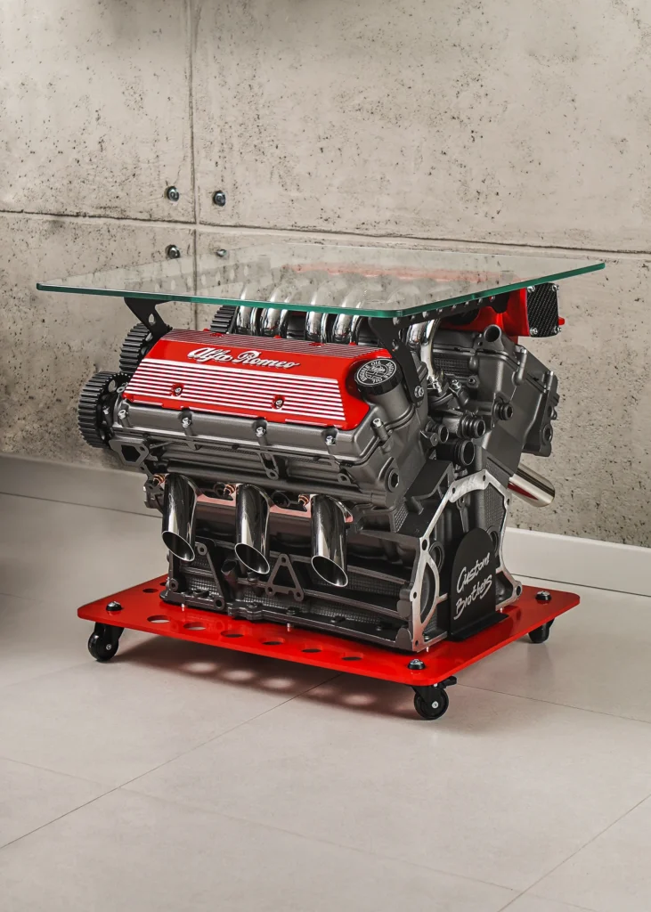 Mesa de centro con motor V6 Busso de Alfa Romeo restaurado, sobre base roja y tapa de cristal