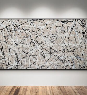 Obra abstracta estilo Jackson Pollock en tonos beige, blanco y negro, colgada en pared blanca con focos de luz