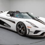 Vista lateral del Koenigsegg Regera 2019 en blanco perla con detalles en negro y dorado, mostrando su silueta agresiva y techo desmontable.