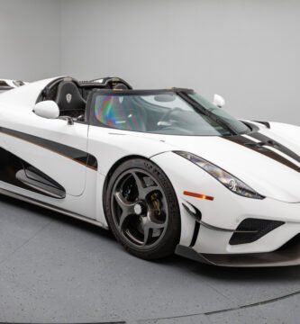 Vista lateral del Koenigsegg Regera 2019 en blanco perla con detalles en negro y dorado, mostrando su silueta agresiva y techo desmontable.