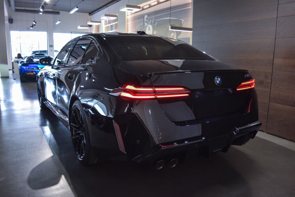 Vista trasera del BMW M5 2025 con pilotos LED encendidos, mostrando las líneas deportivas del sedán