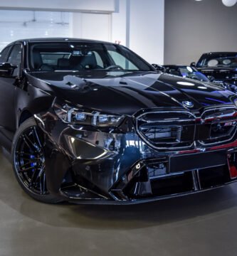 Vista frontal del BMW M5 2025 en color negro brillante, expuesto en un concesionario de lujo.