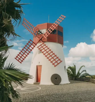 Molino de viento restaurado con aspas rojas en Azores, rodeado de vegetación tropical