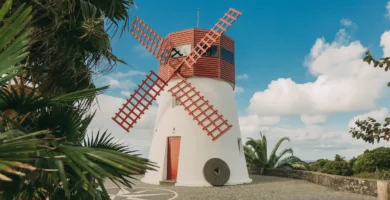 Molino de viento restaurado con aspas rojas en Azores, rodeado de vegetación tropical